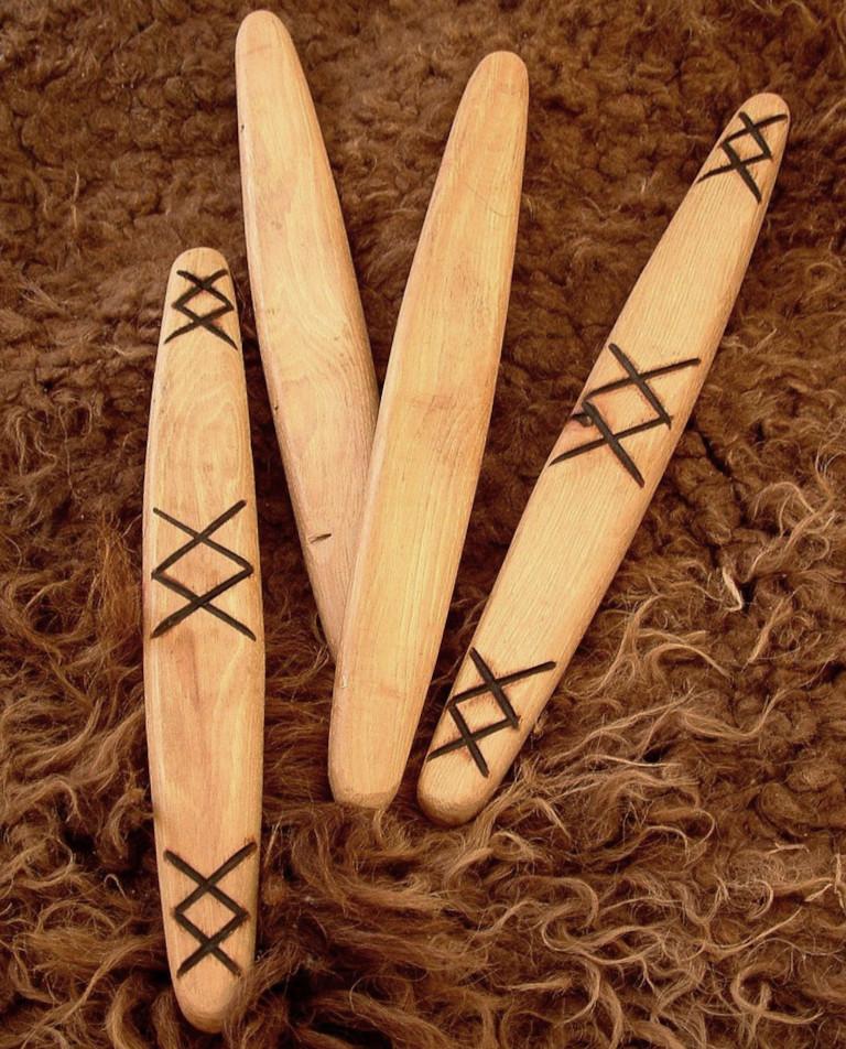 Photo of wooden throwing stick dice with one side marked, and the other side left blank