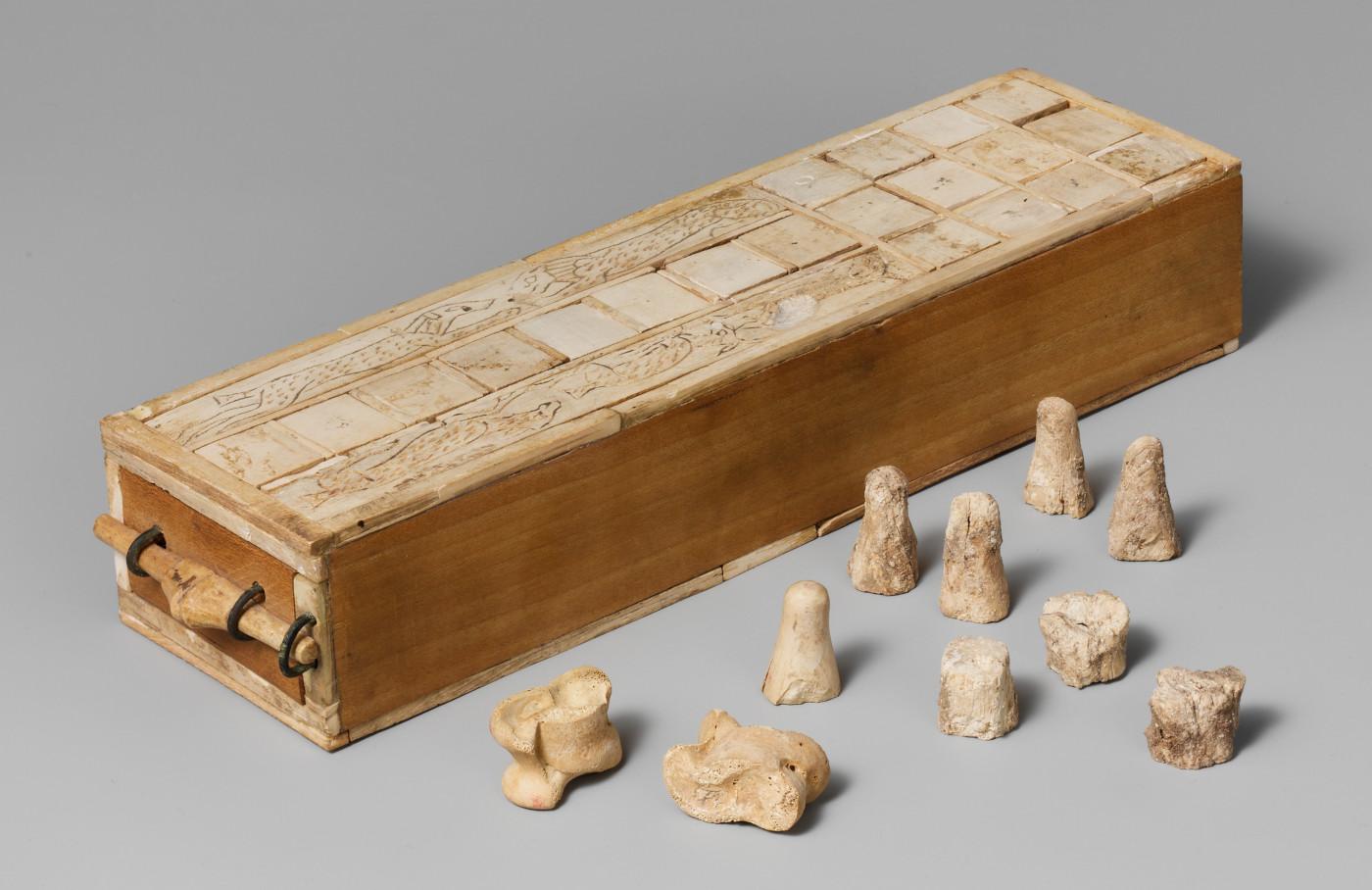 Photo of an Aseb board, with pieces and knucklebones laid out in front of the board